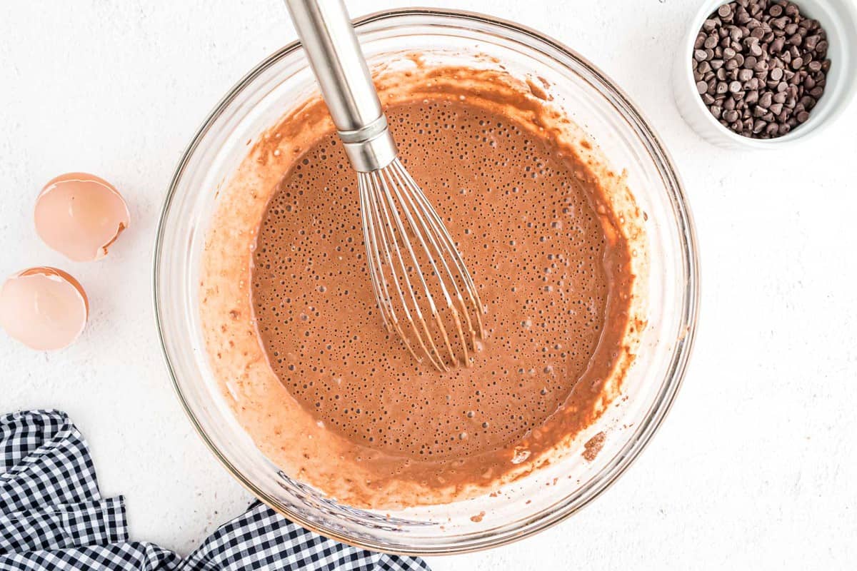 Masa de panqueque de chocolate con un batidor.