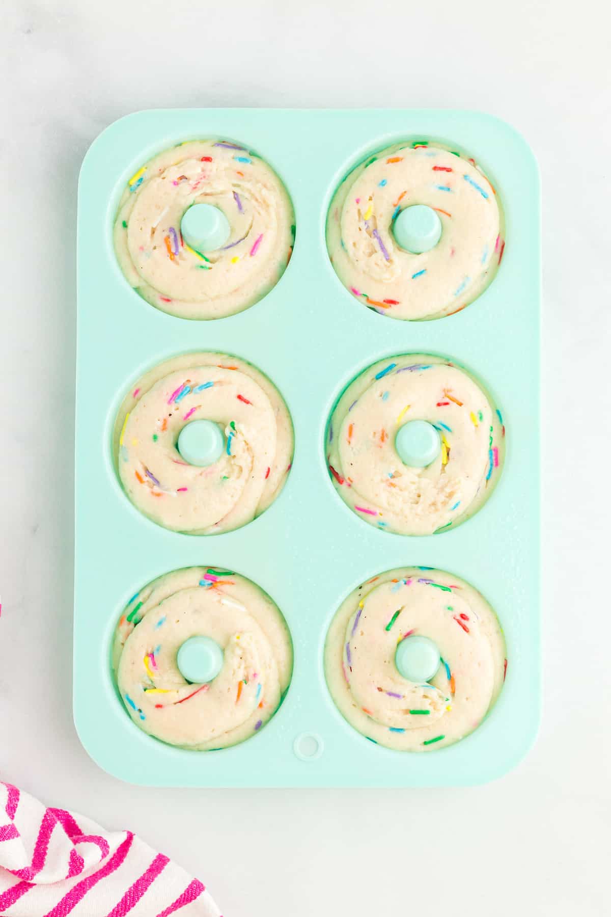 Donuts sin hornear en un molde de silicona azul.