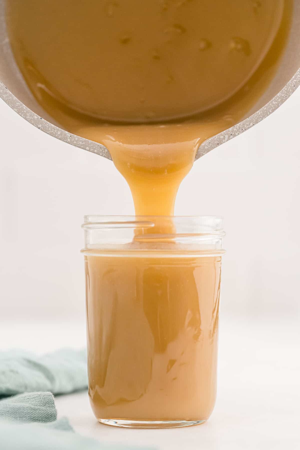 Salsa de caramelo vertiéndose de una sartén a un frasco de cristal.