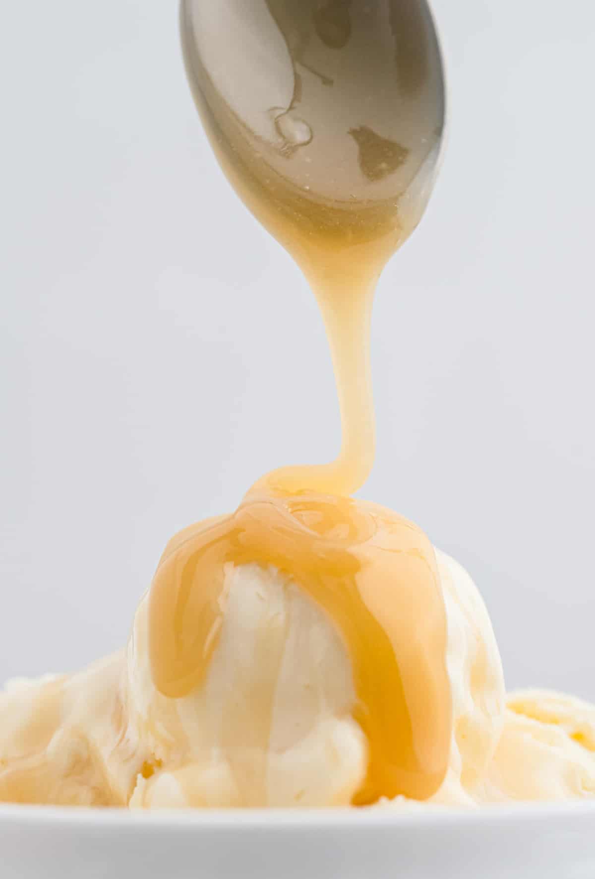 Caramelo siendo rociado sobre helado de vainilla.