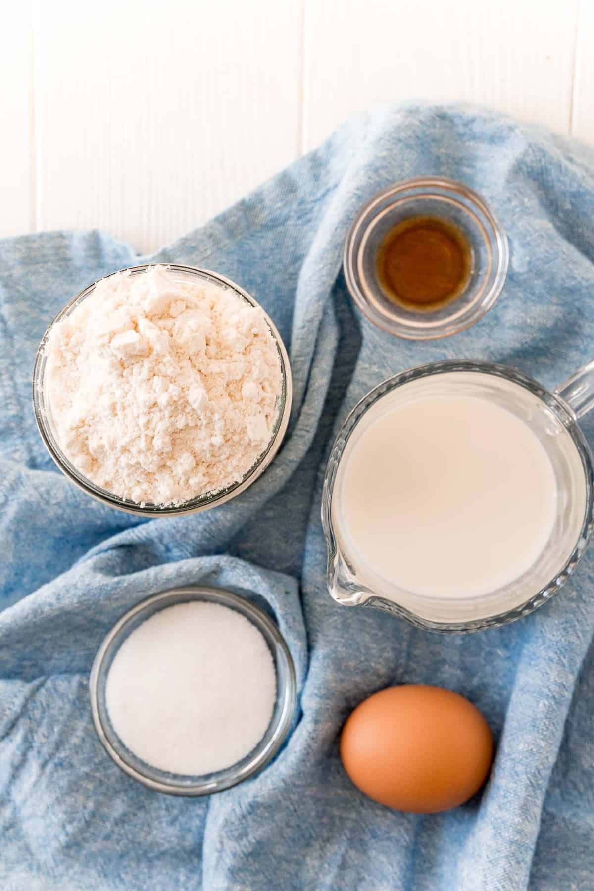 Vista superior de los ingredientes: Leche, bisquick, vainilla, azúcar, huevo.