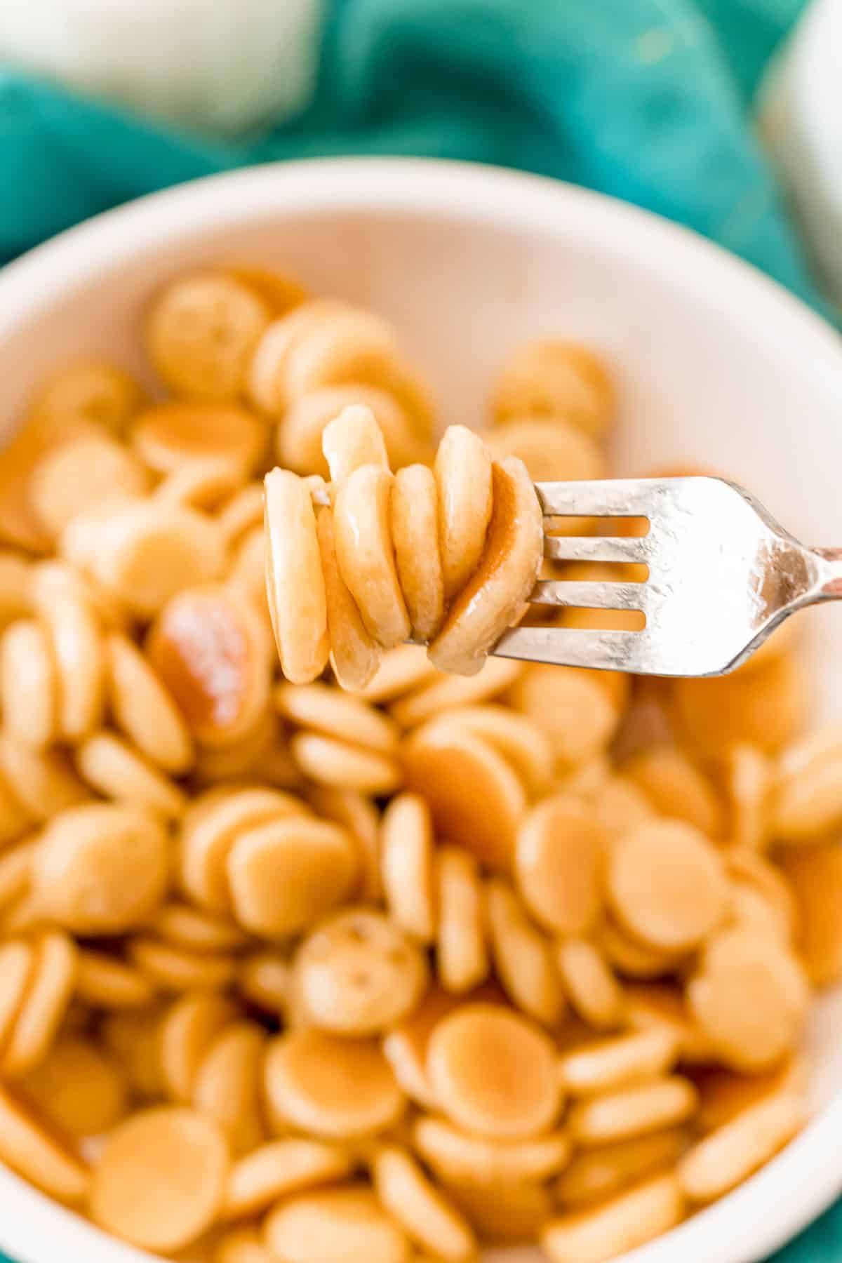 Mini panqueques en un tenedor, sostenido sobre un tazón de más.