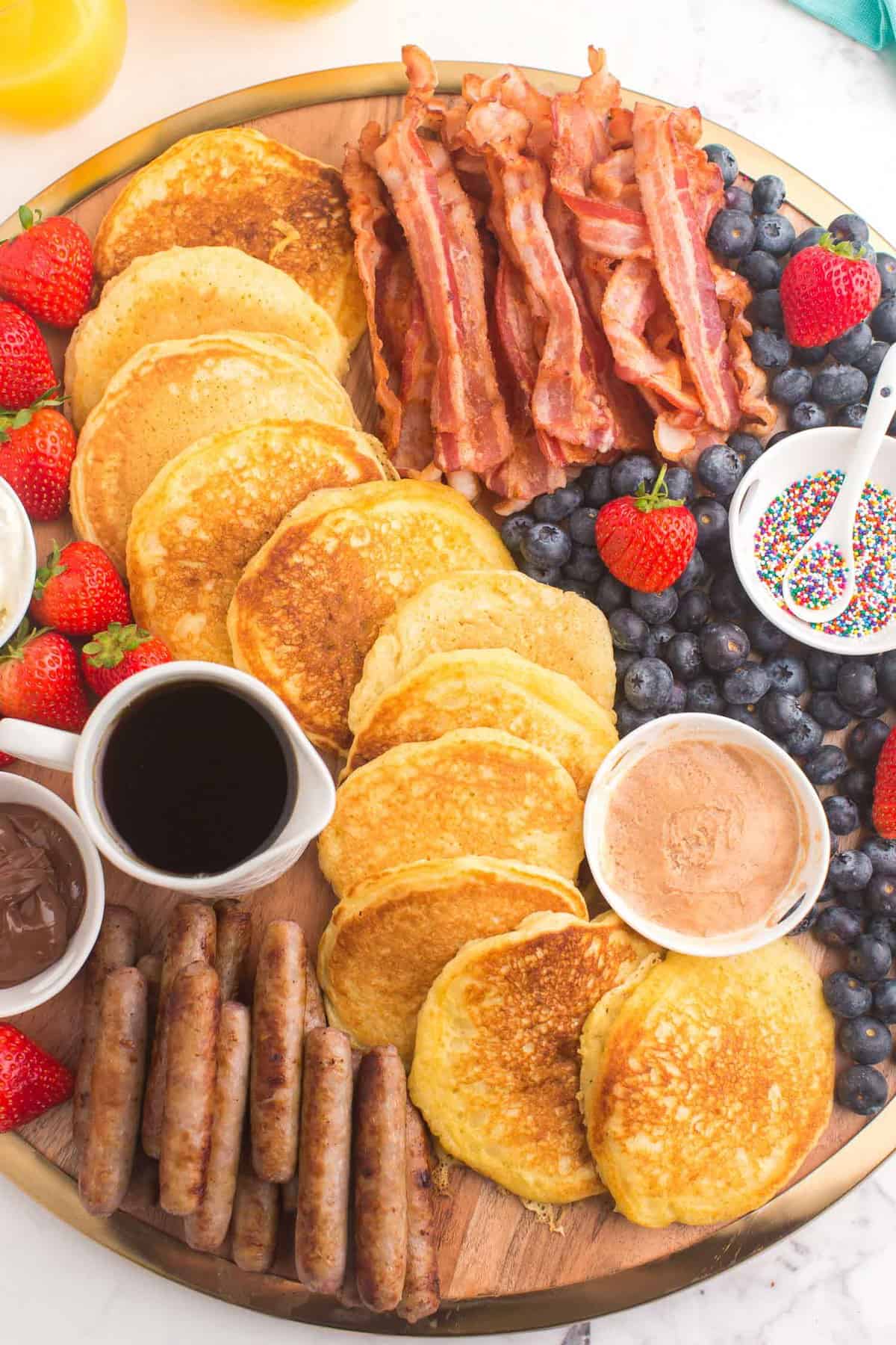 Primer plano de panqueques, arándanos, tocino, salchichas y coberturas.
