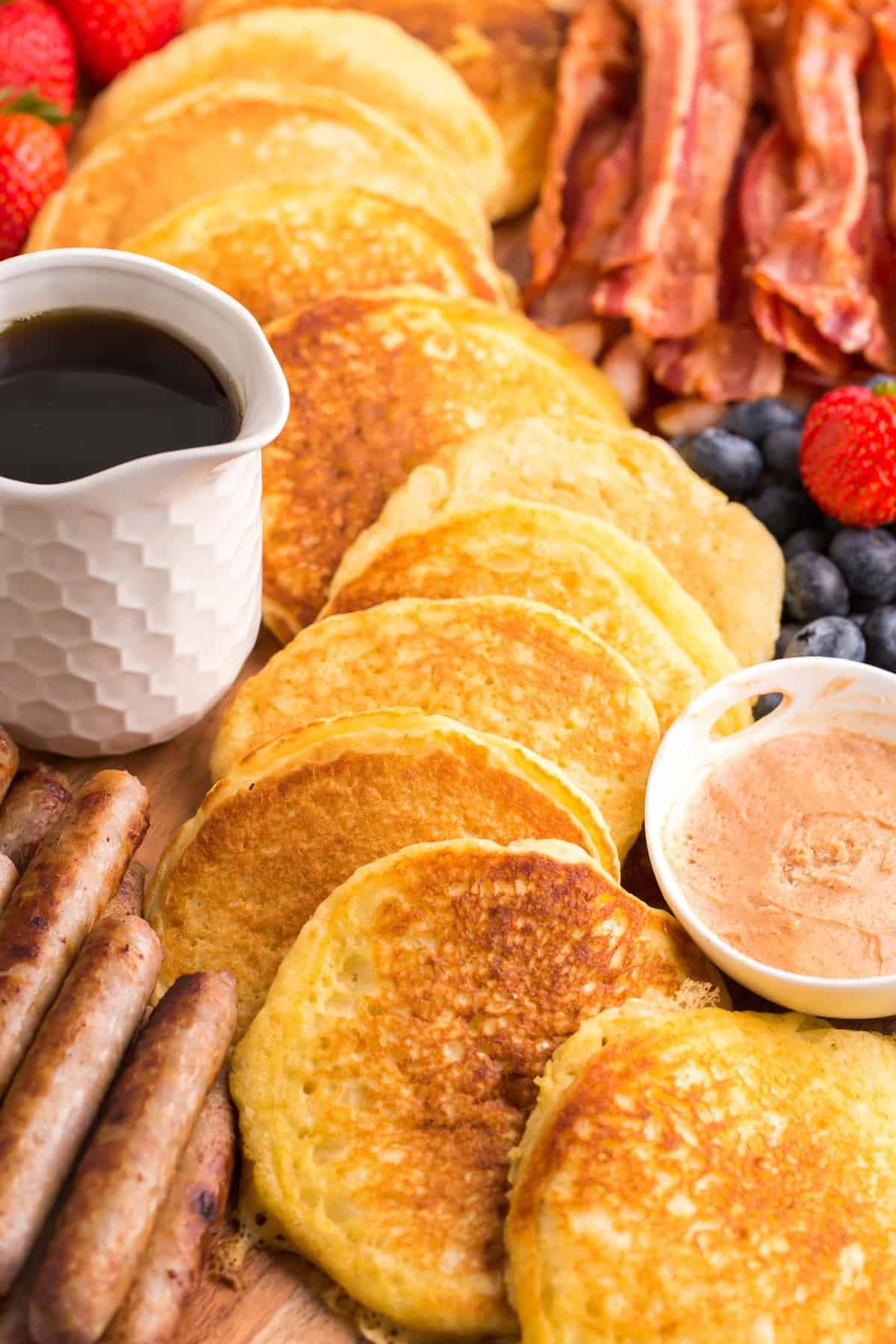 Primer plano de panqueques en un patrón decorativo rodeados de otros elementos del desayuno.