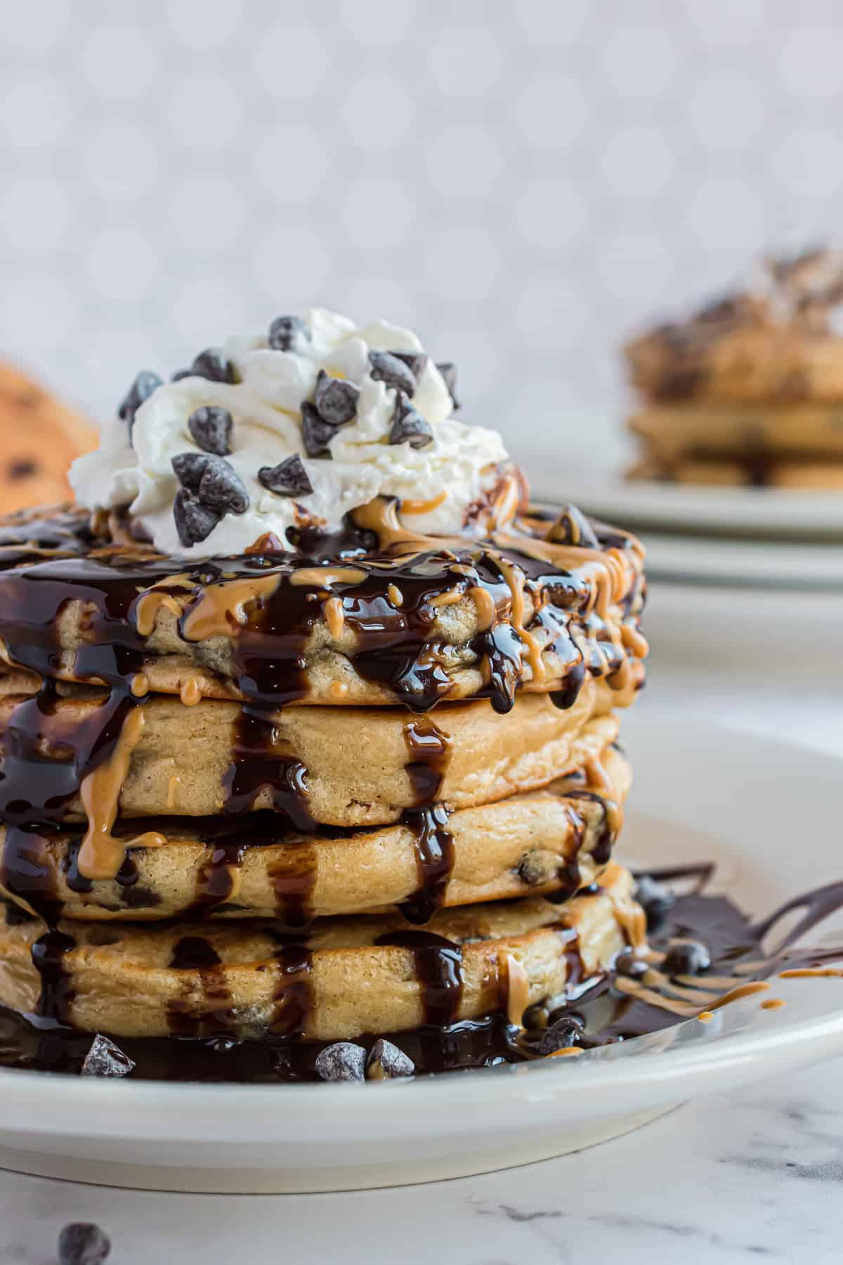 Pila de panqueques con salsa de chocolate y crema batida.