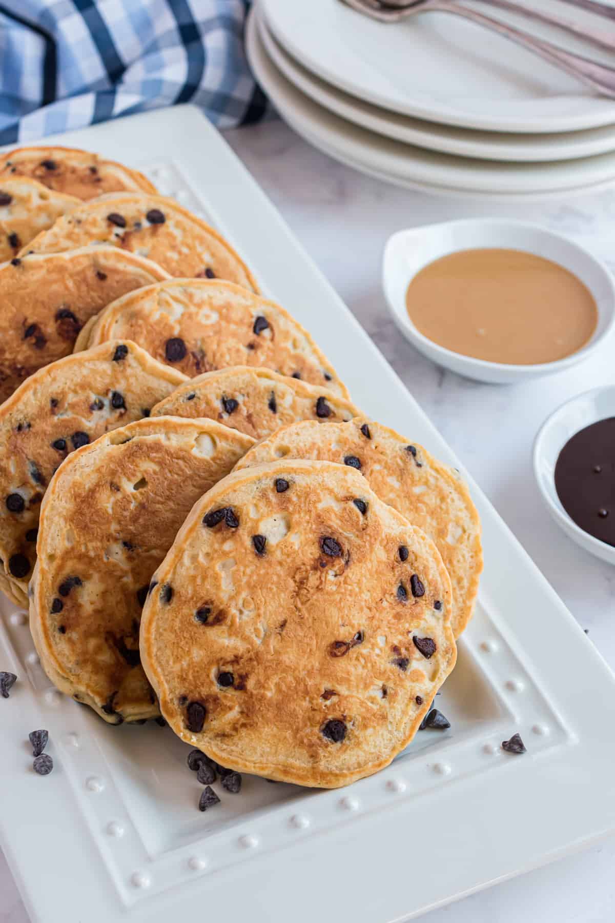Panqueques decorados con chips de chocolate en una bandeja blanca.