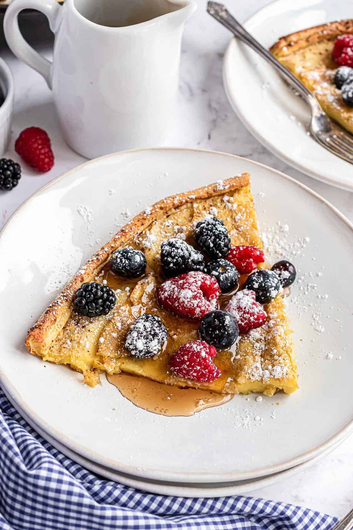 Rebanada triangular de panqueque Dutch baby en un plato blanco.