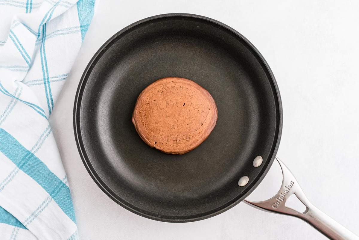 Panqueque de chocolate cocido en una pequeña sartén negra.