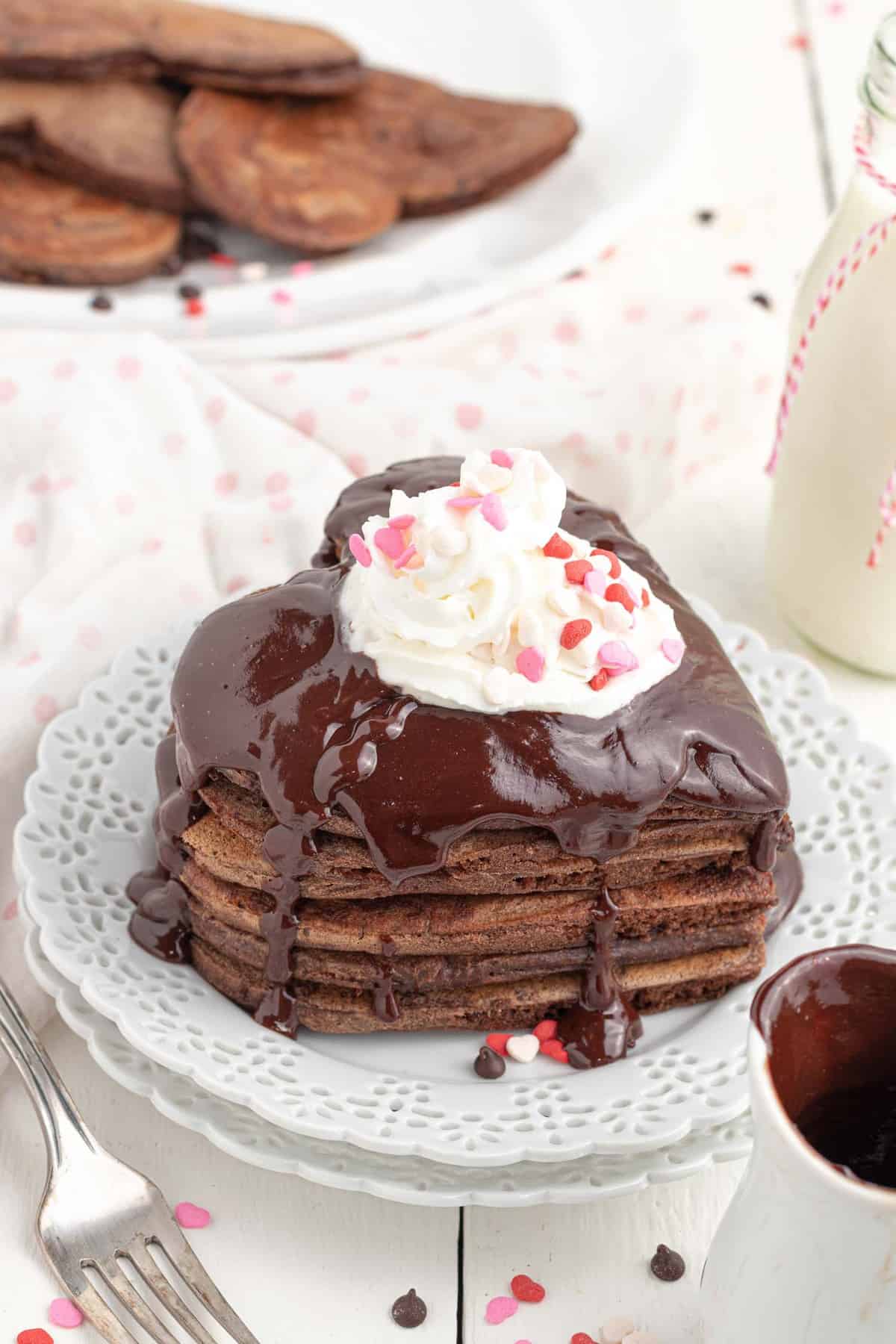 Montón de panqueques en forma de corazón, con crema batida y chispas.