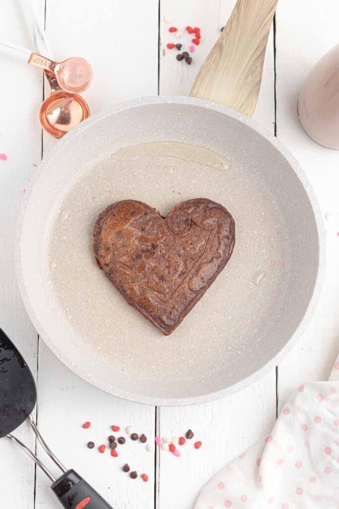 Panqueque de chocolate en forma de corazón en una plancha blanca.