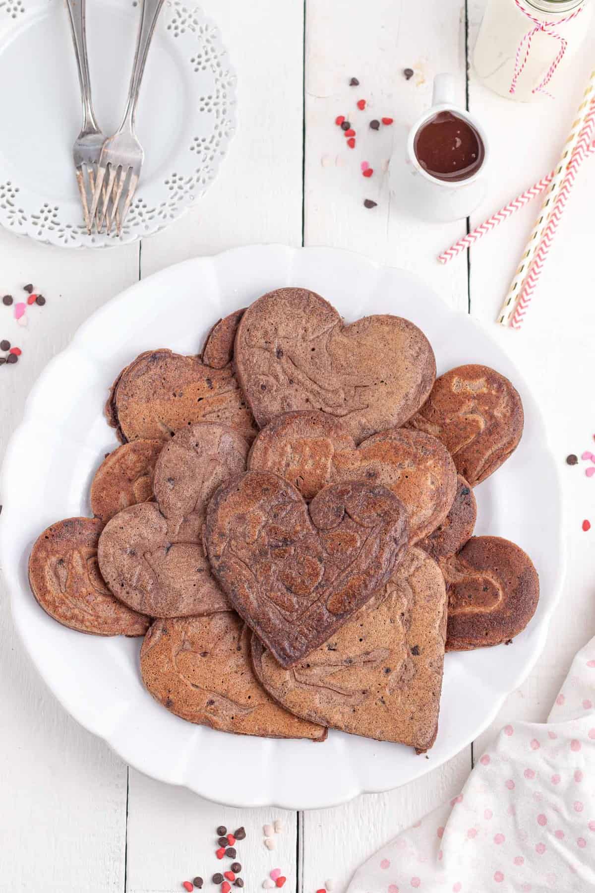 Montón desordenado de panqueques de chocolate en un plato. Los panqueques son en forma de corazón.