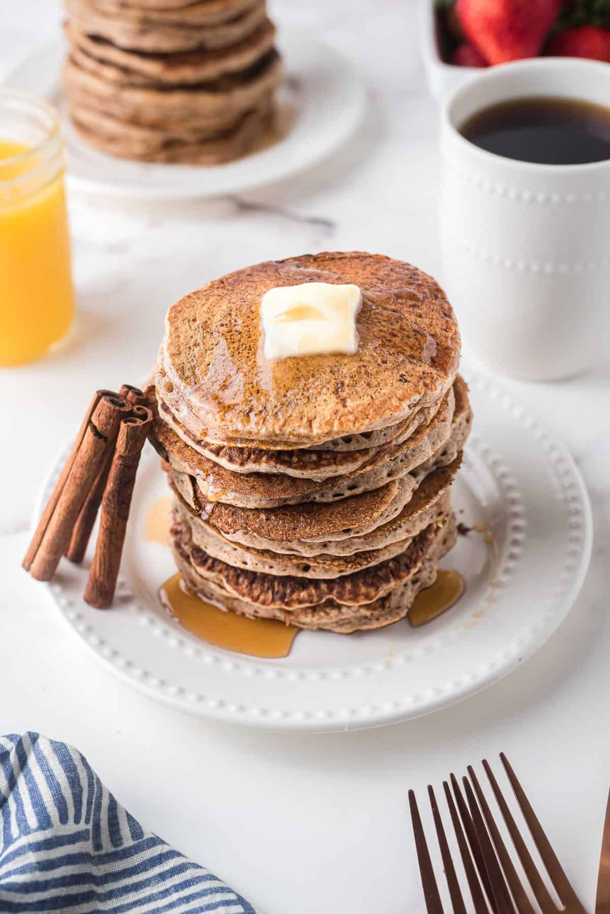 Gran montón de panqueques con palitos de canela apoyados contra él.