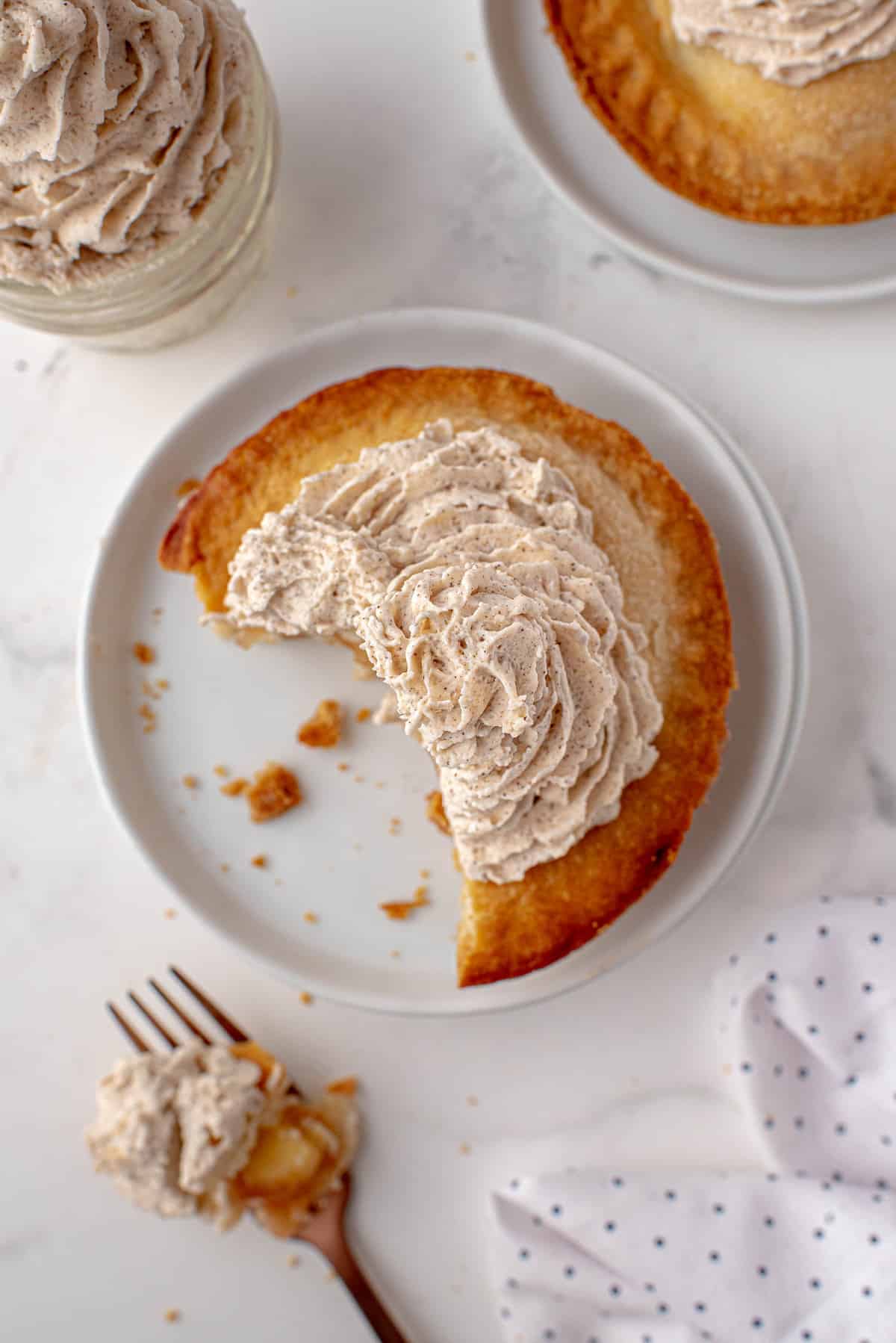 Tarta de manzana individual en un plato blanco, con crema batida.