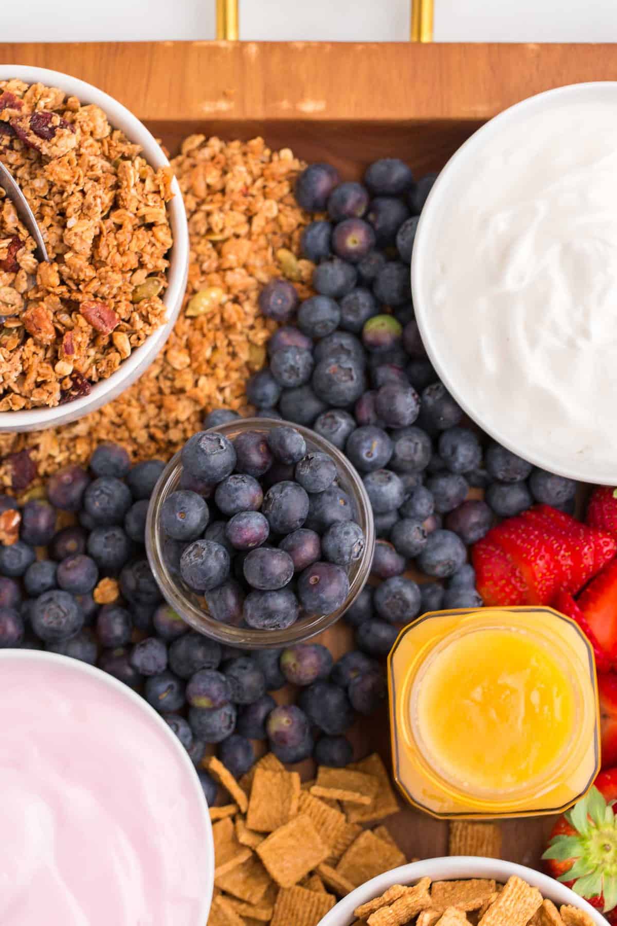 Arándanos, yogurt, granola y crema de limón en una bandeja.