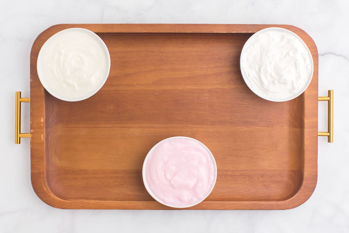 Tres tazones de yogurt en una tabla de madera.