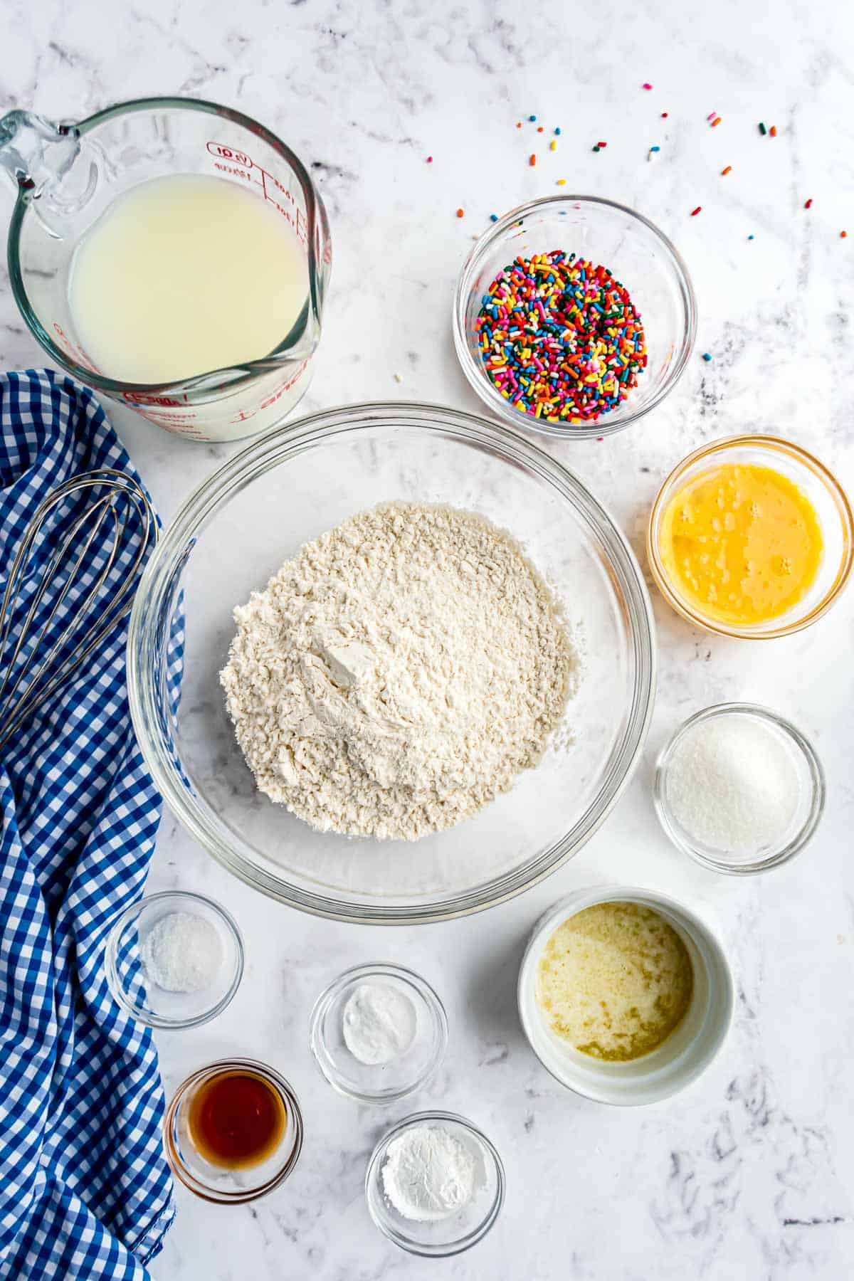 Bols transparentes con ingredientes: harina, huevos, vainilla, leche, chispas y más.