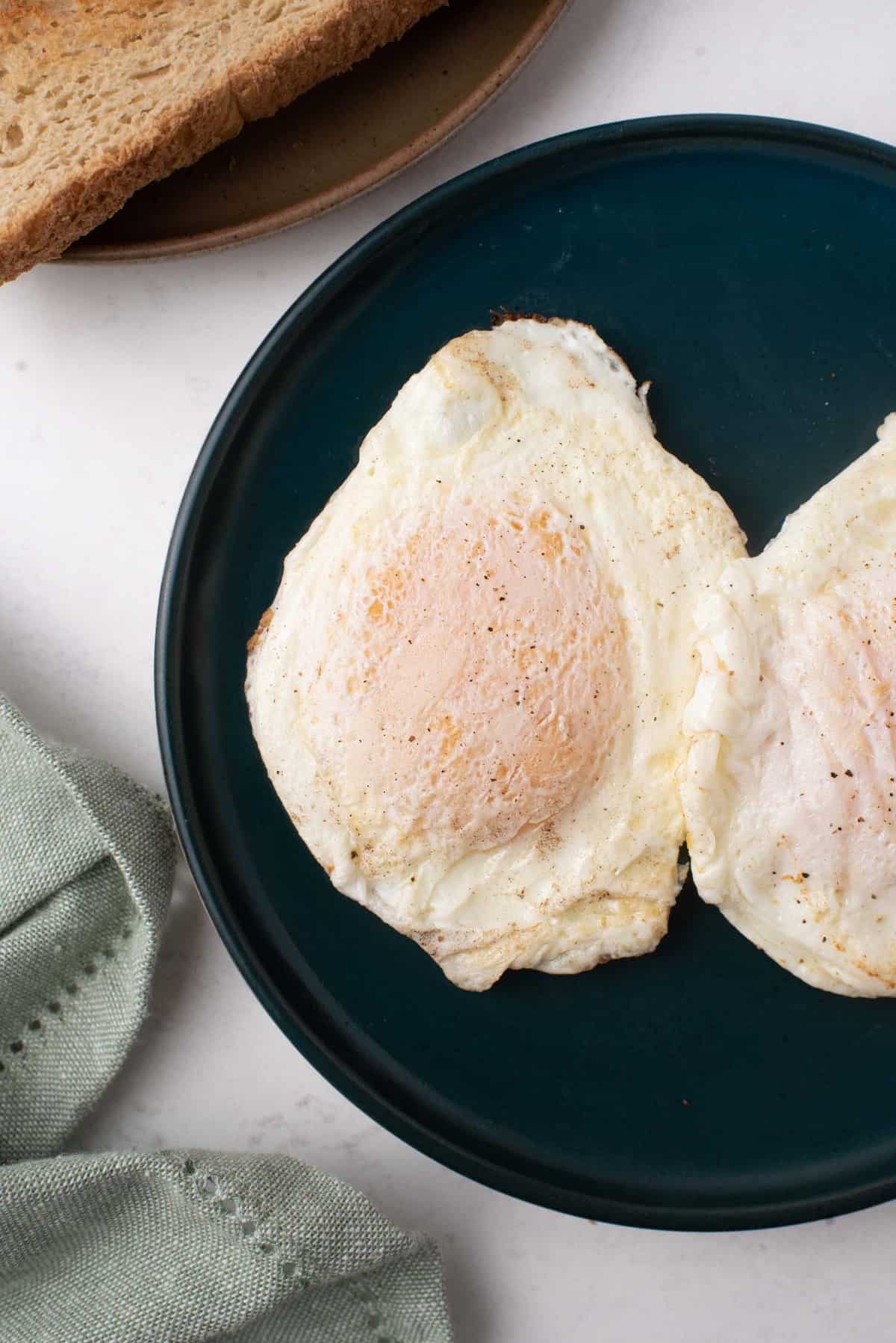 Dos huevos en un plato de color oscuro.