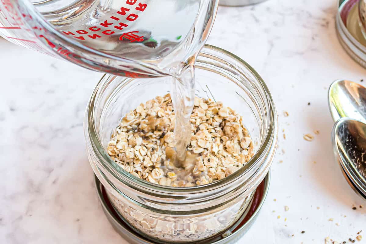Agua caliente siendo añadida a un pequeño frasco de avena.