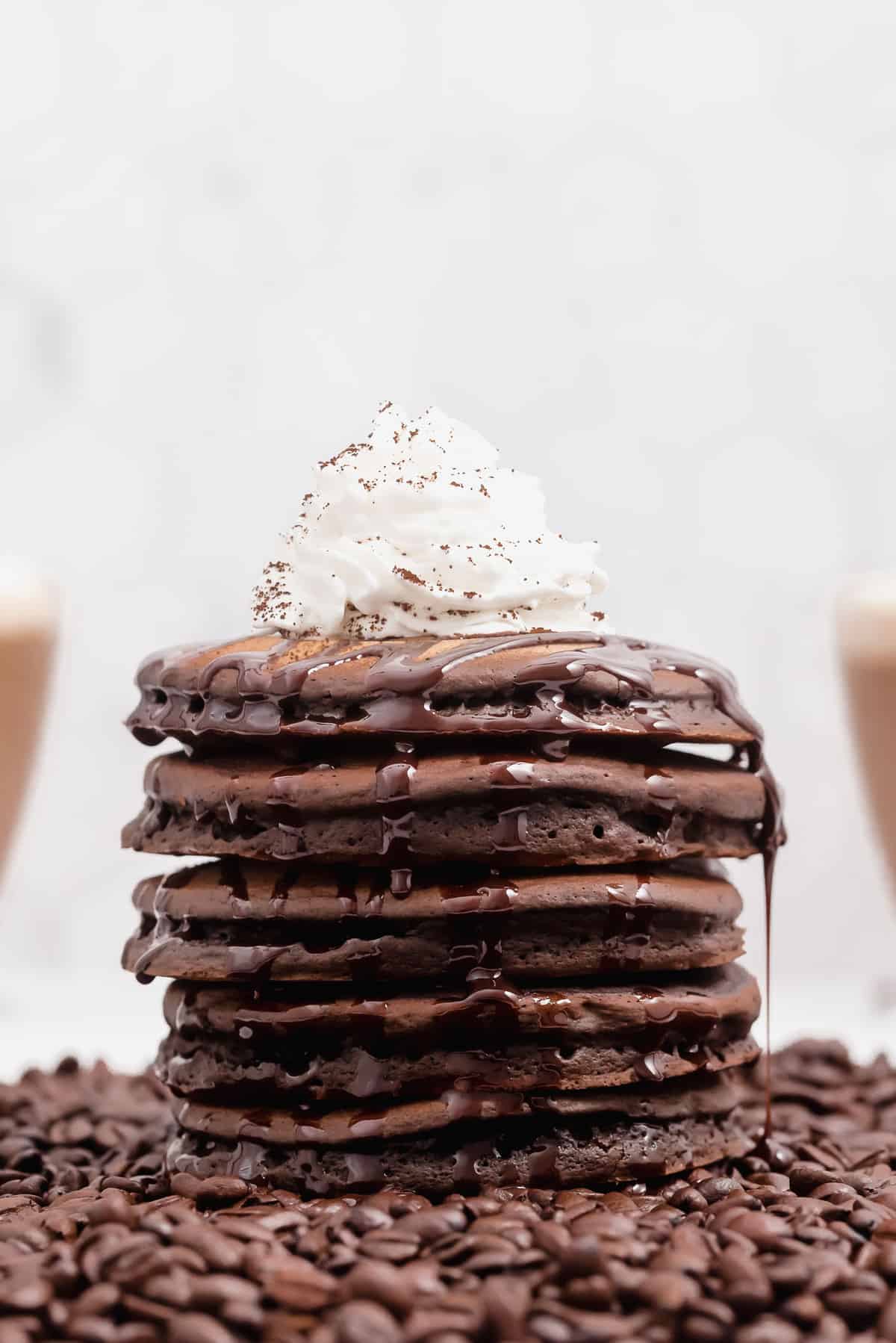Panqueques sobre granos de café, goteando con jarabe de chocolate.
