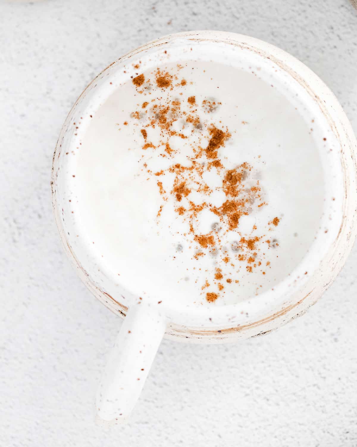 Vista aérea de un latte de especias de calabaza en una taza blanca.