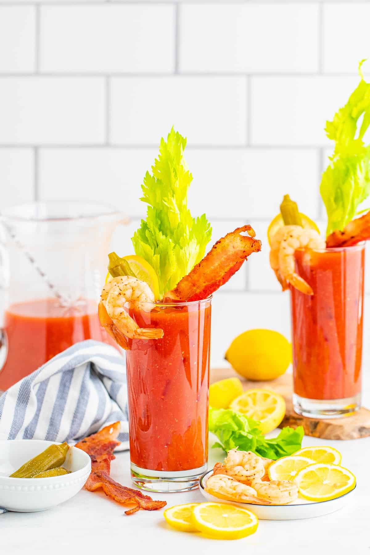 Dos copas de bloody mary sobre hielo con decoraciones.