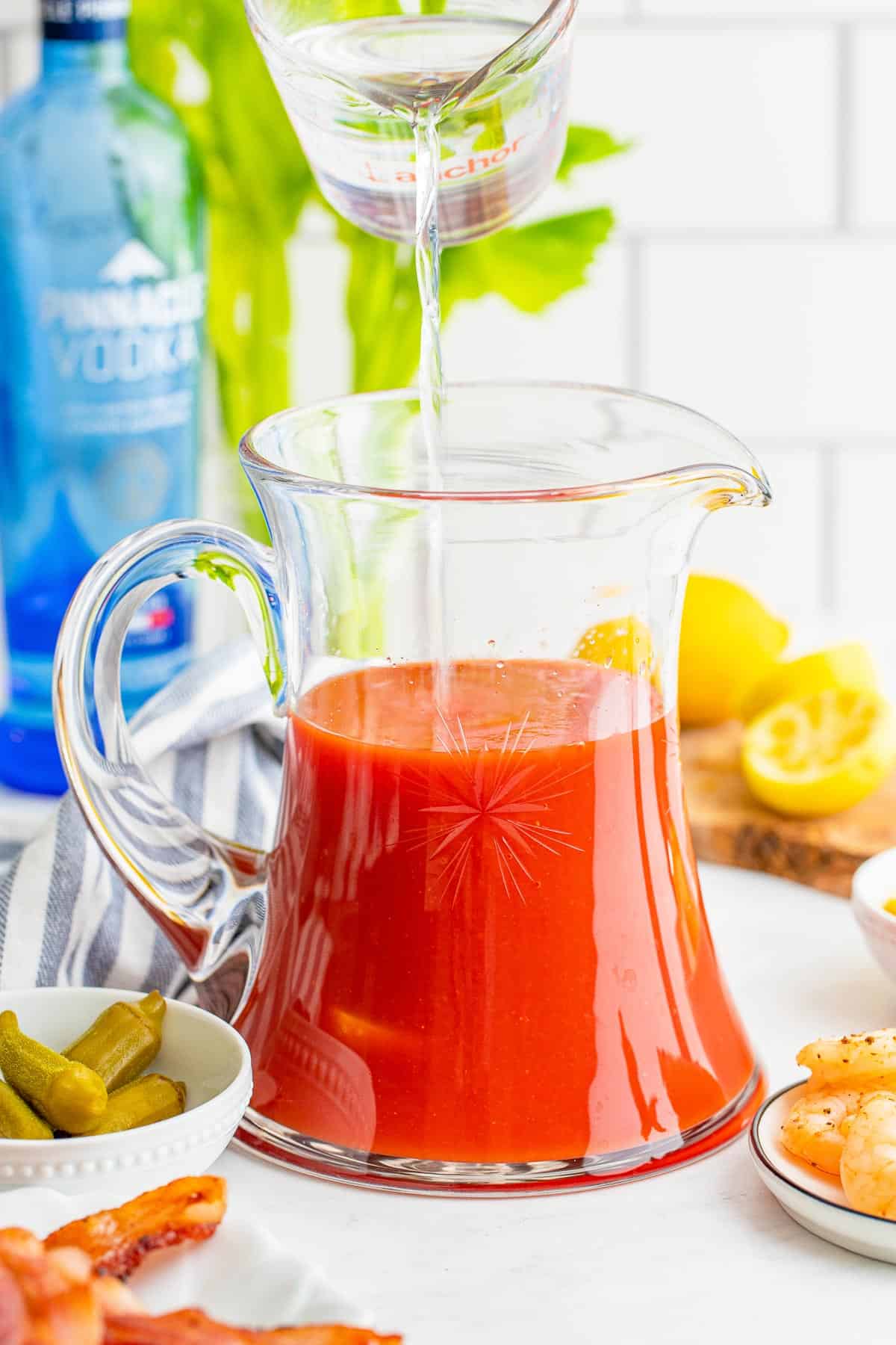 Vodka siendo vertido en una jarra de jugo de tomate.