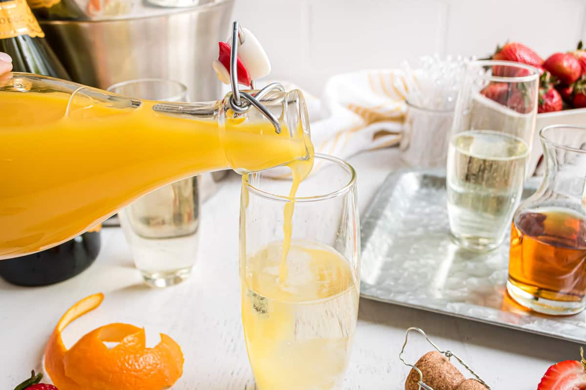 Jugo de naranja siendo vertido en un vaso con prosecco.
