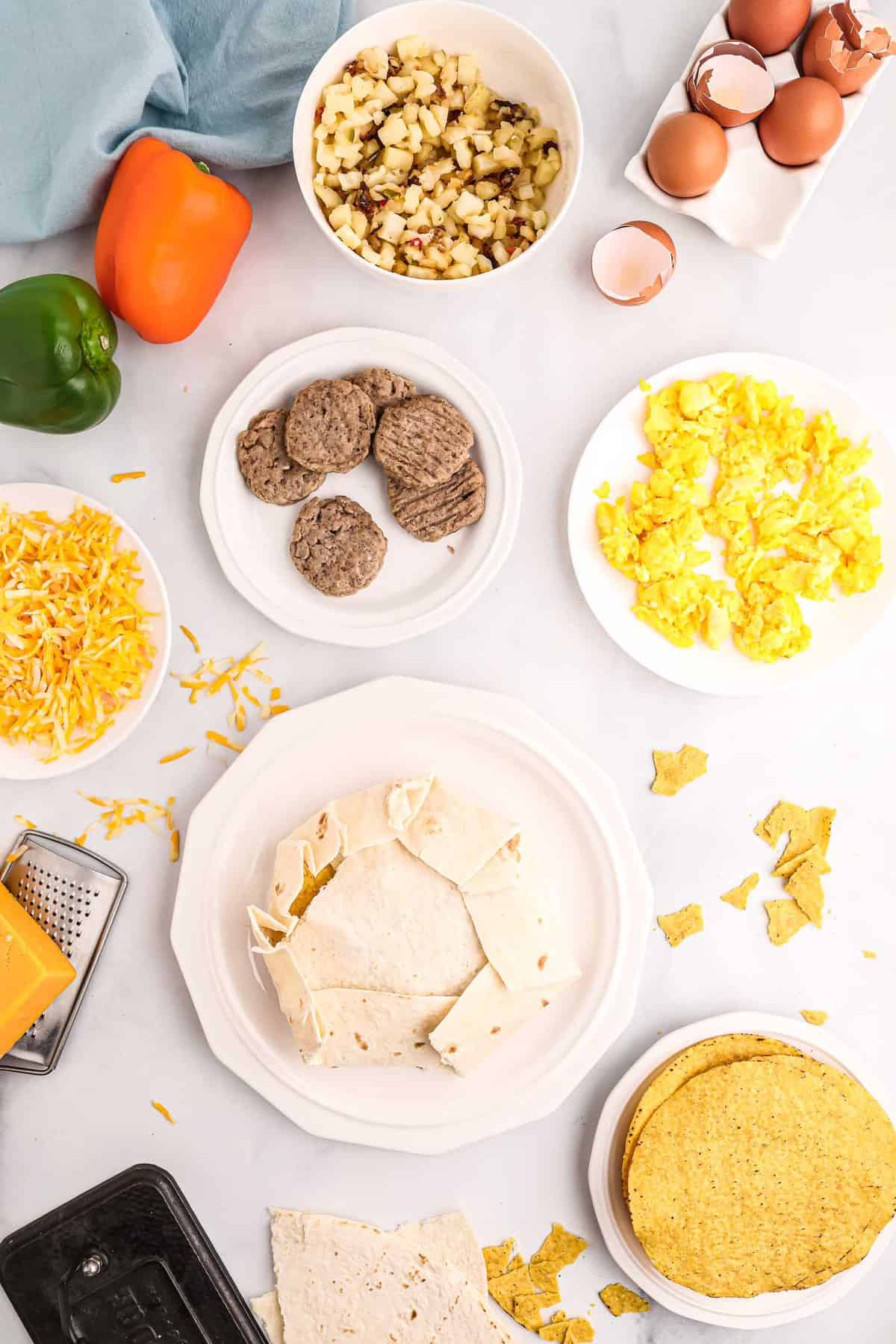 Crunchwrap sin cocinar, rodeado de ingredientes que incluyen huevos, salchicha, papas hash.