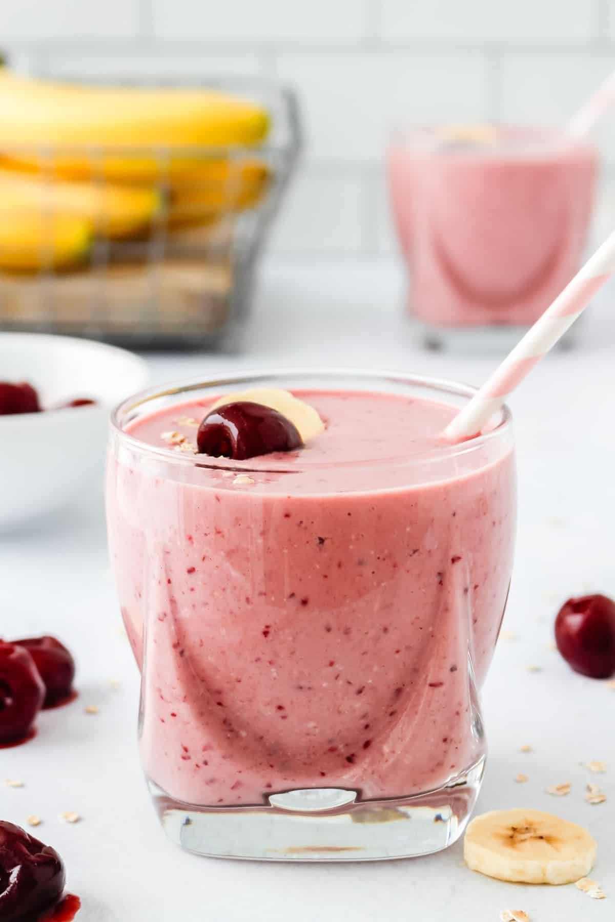 Batido de cereza en un vaso corto transparente, otro en el fondo.