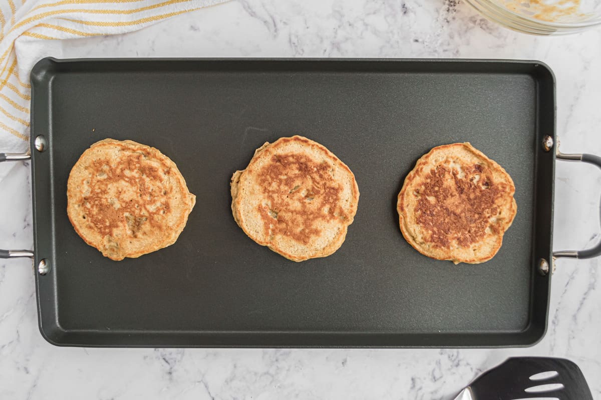 Panqueques cocinados en una plancha negra.