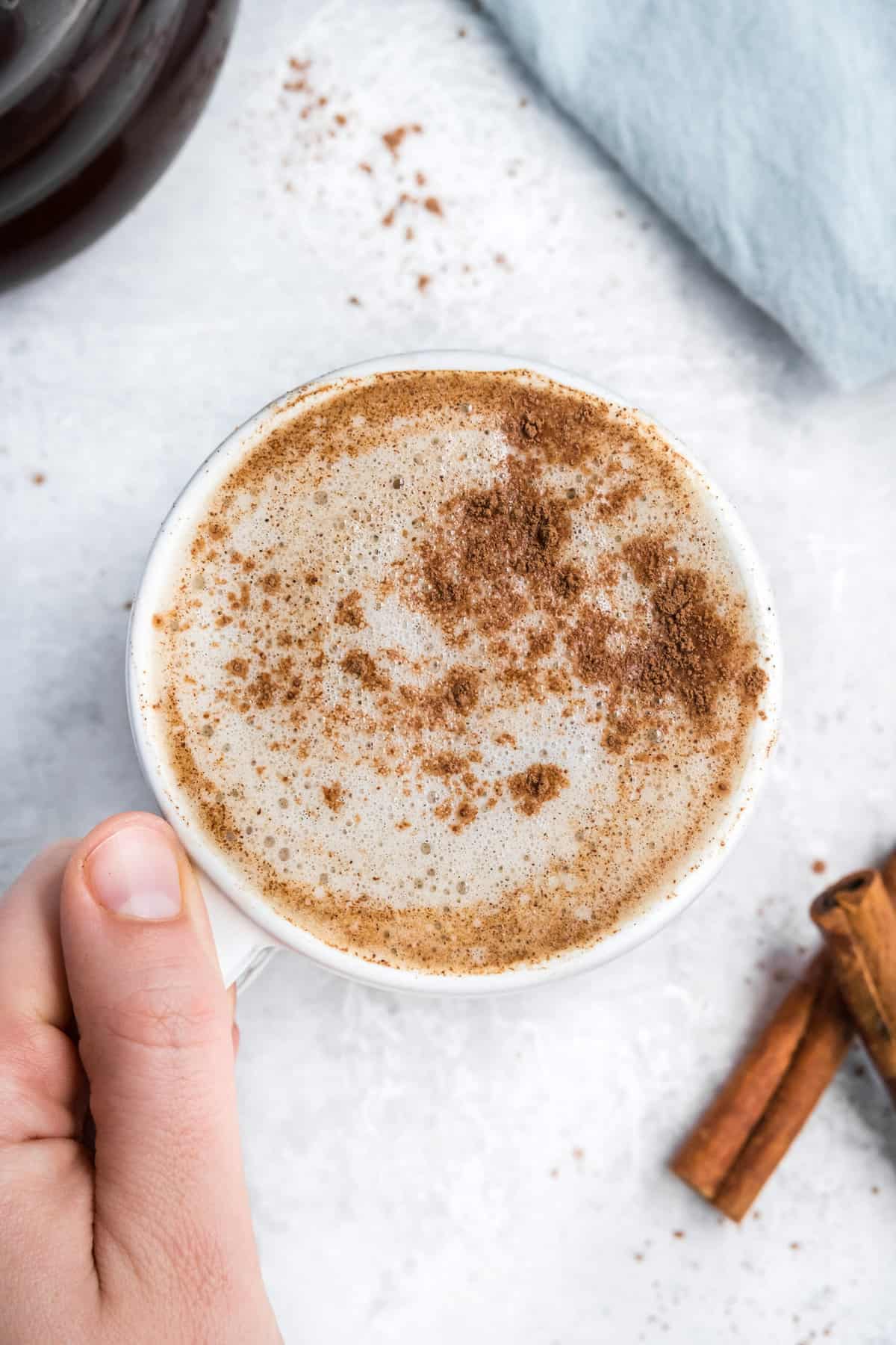 Una mano sosteniendo una taza de chocolate caliente mexicano.