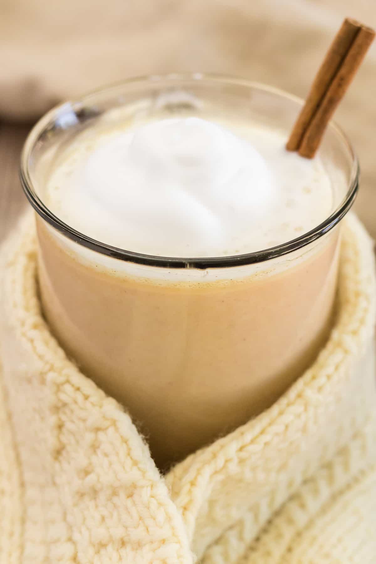 Chocolate caliente de calabaza envuelto en una manta o suéter.