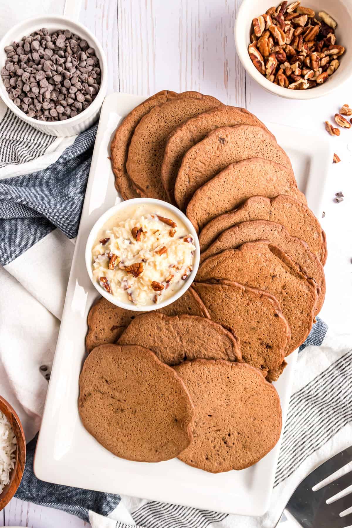 Plato de panqueques de chocolate con un topping de chocolate alemán en un tazón pequeño.