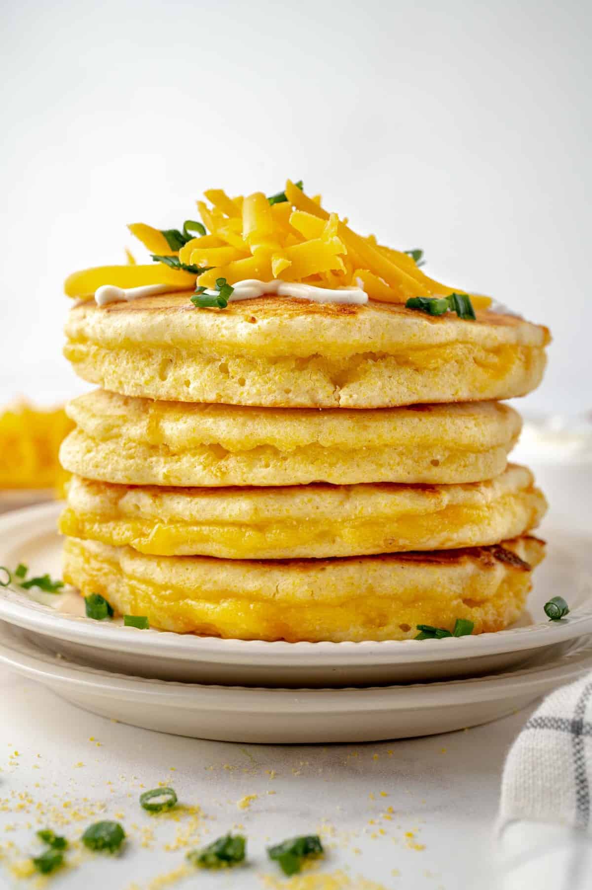 Panqueques apilados, cubiertos con queso y cebollino.
