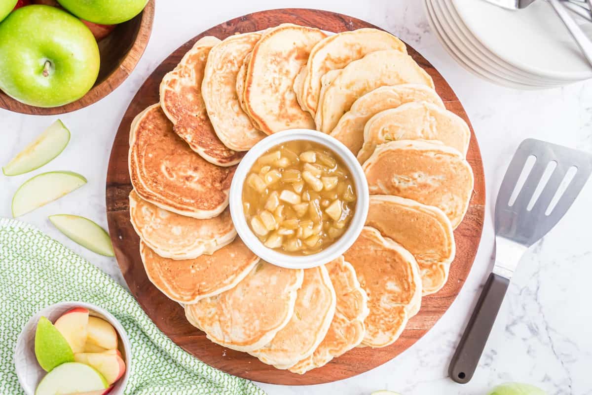 Panqueques en una fuente con salsa de manzana con caramelo en el medio.