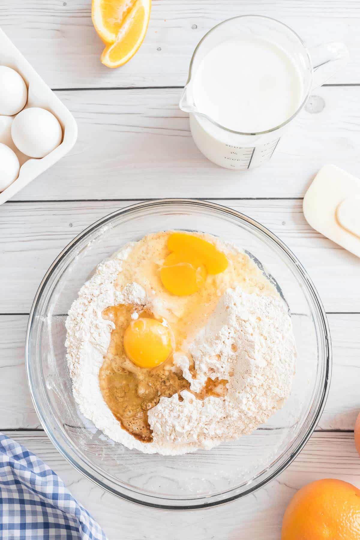 Ingredientes secos y húmedos para los panqueques de naranja en un gran bol de vidrio.