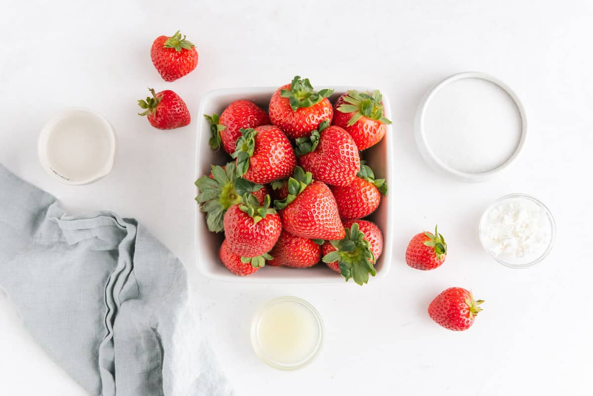 Vista aérea de fresas frescas, azúcar, jugo de limón, maicena y agua.