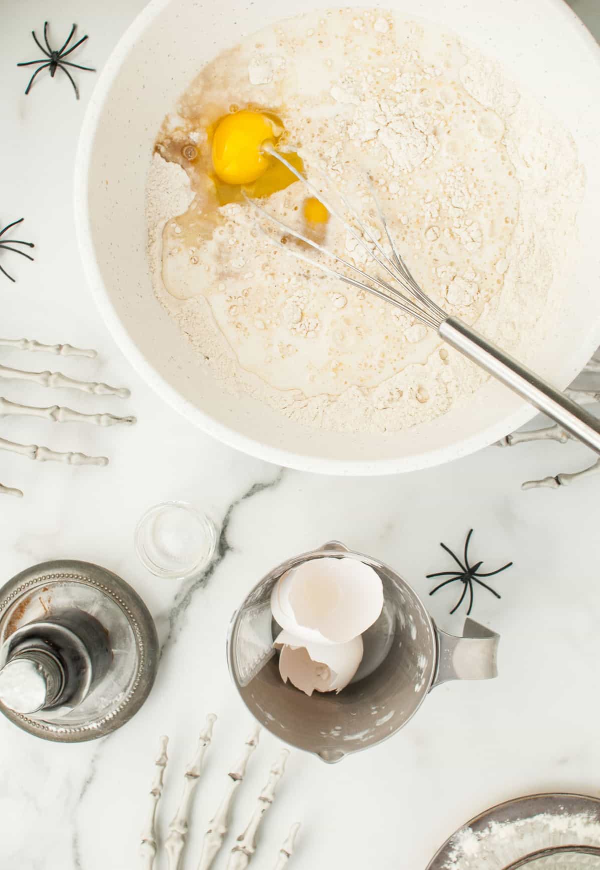 Ingredientes secos de panqueques en un tazón blanco con huevos y leche añadidos.