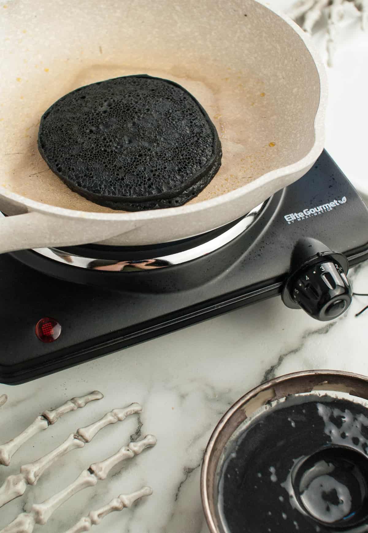 Panqueque negro cocido en una sartén blanca.