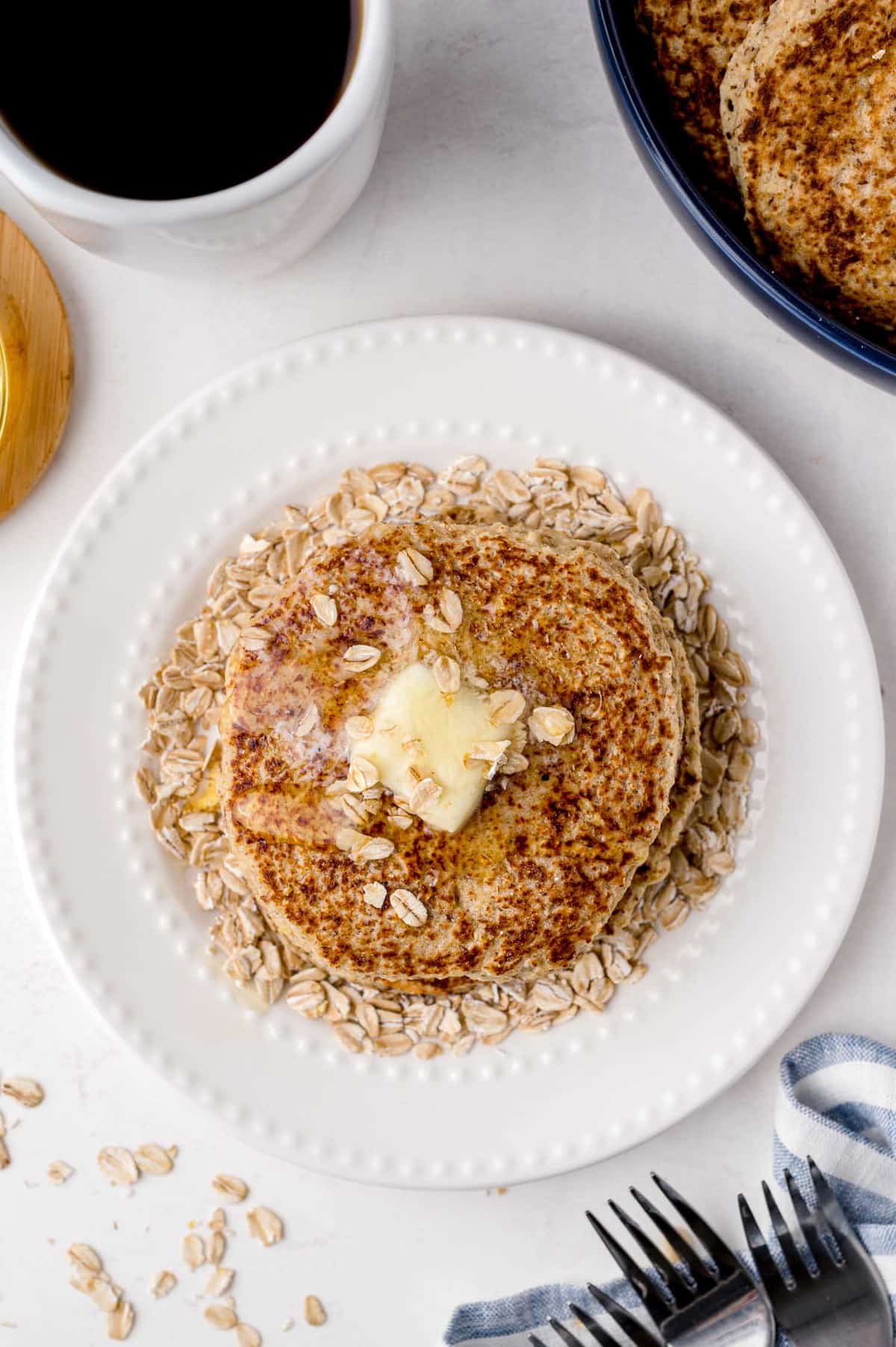 Vista superior de una pila de panqueques con mantequilla, miel y avena.