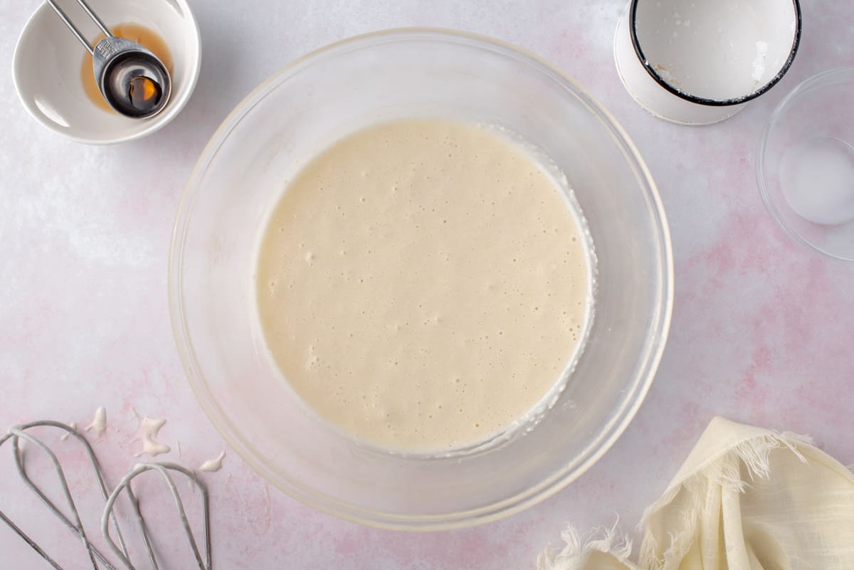 Glaseado de crema de queso en un tazón de mezcla de vidrio transparente.
