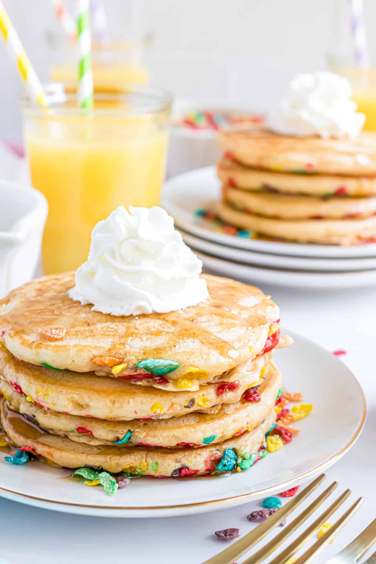 Panqueques de fruity pebbles apilados y cubiertos con crema batida.