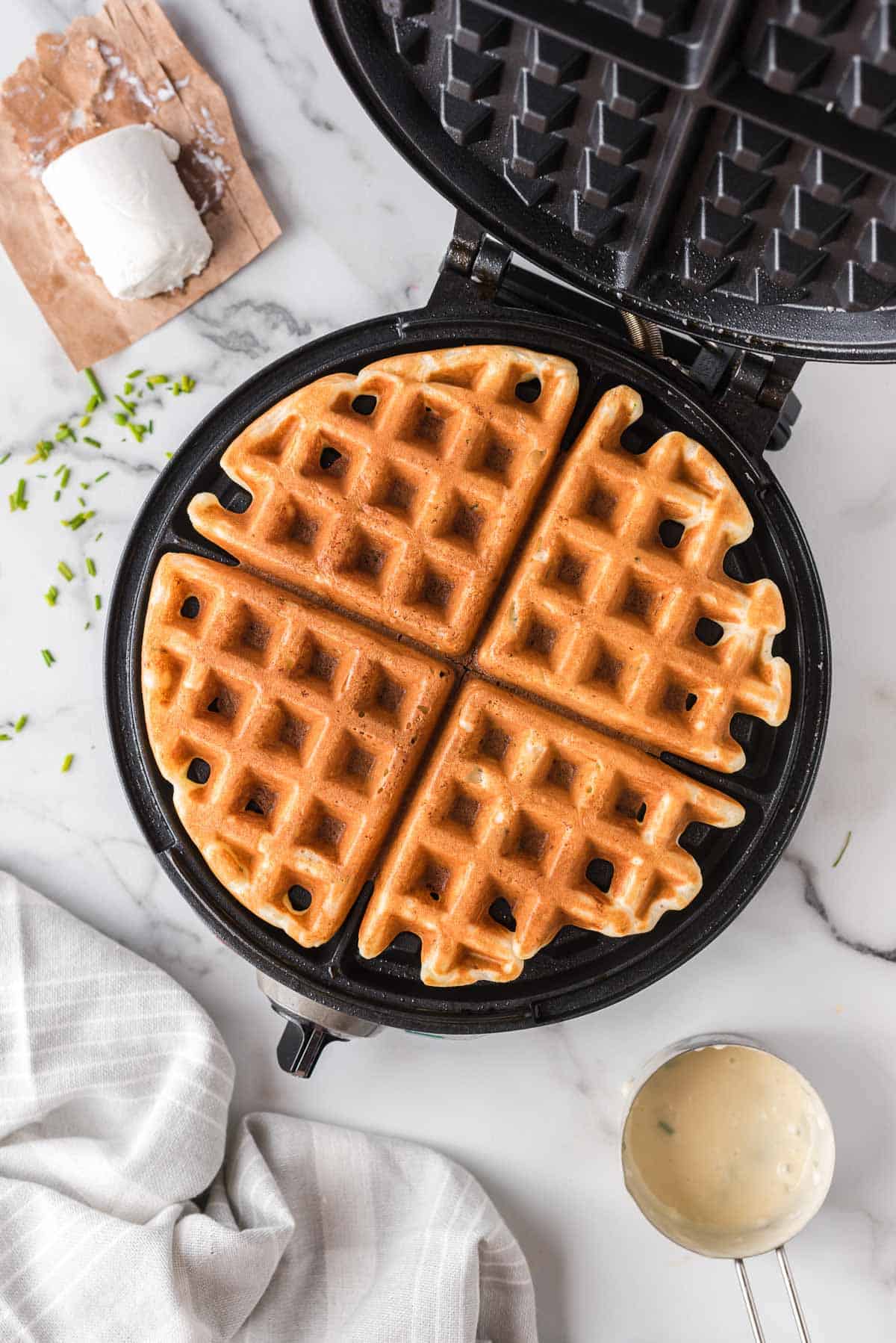 Vista aérea de un panqueque en una wafflera, rodeado de ingredientes.