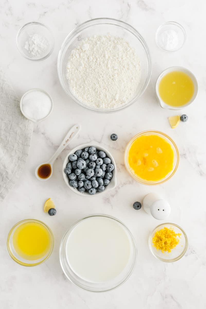 Ingredientes para panqueques de limón con frescos arándanos. Todos los ingredientes están en pequeños cuencos de vidrio transparentes.