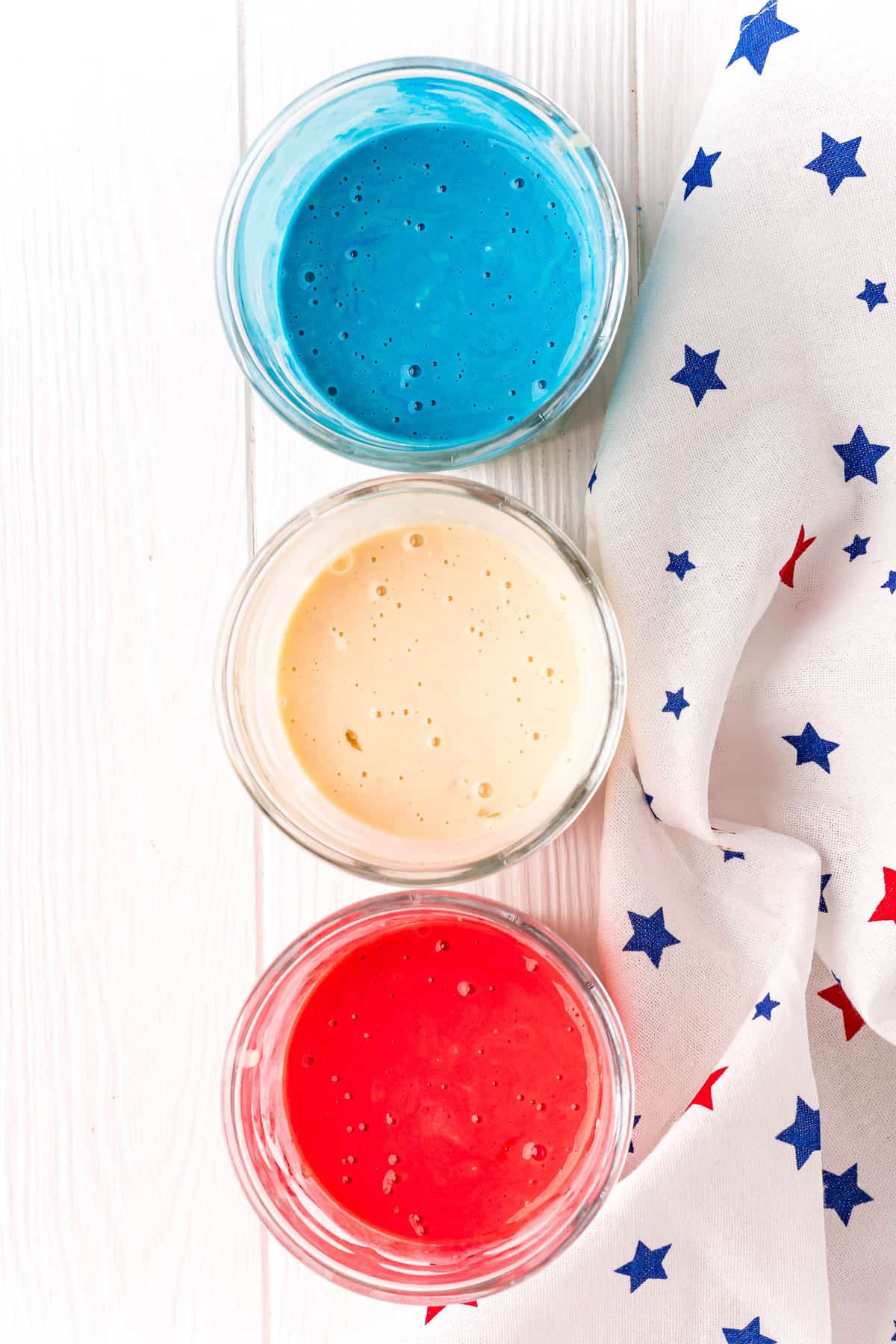 Tres tazones de mezcla de panqueques, uno azul, uno blanco, uno rojo.