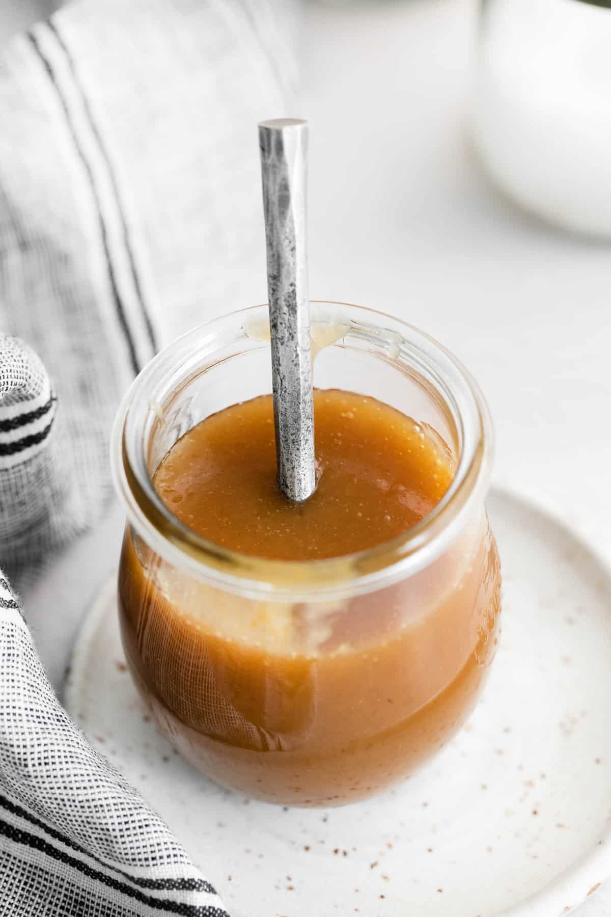 Caramelo en un pequeño tarro de vidrio con una cuchara de plata.