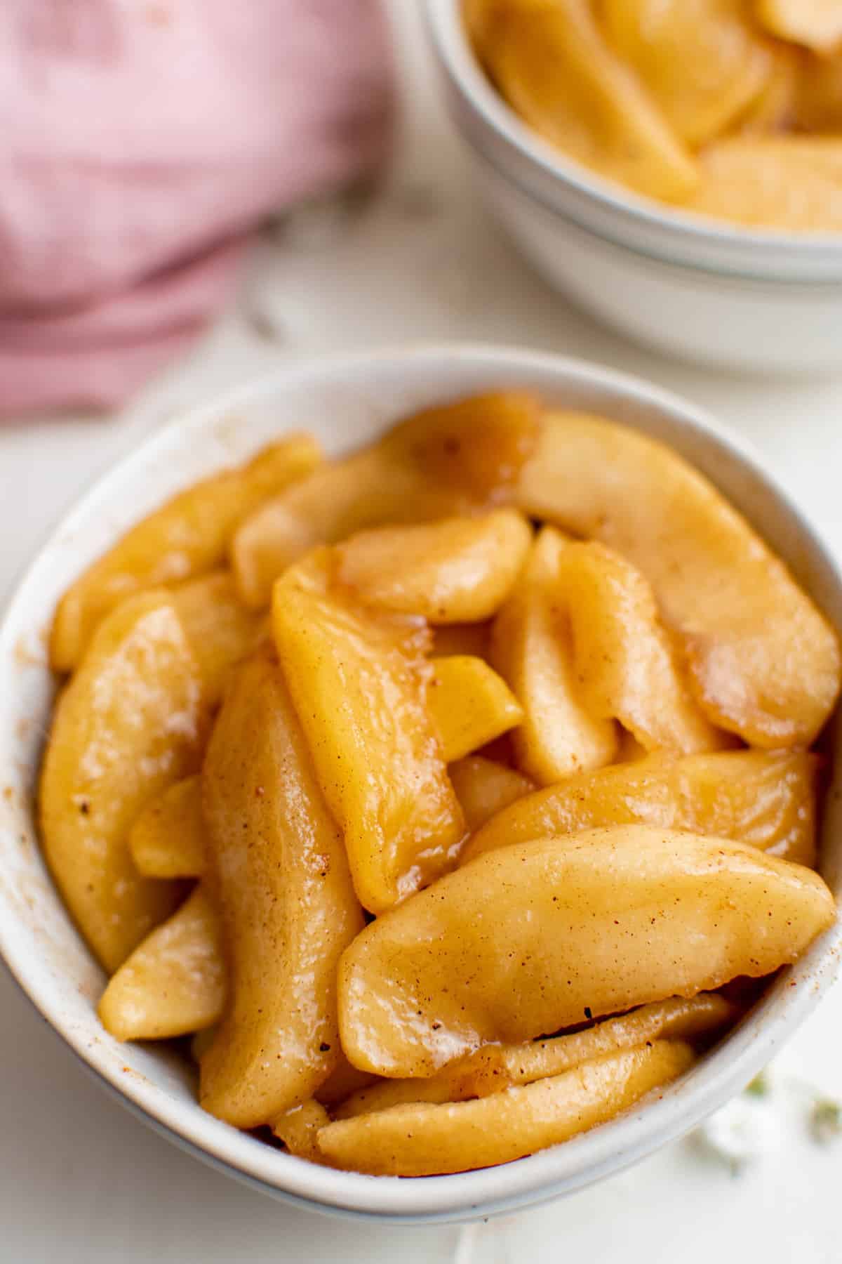 Manzanas fritas en un pequeño tazón blanco.