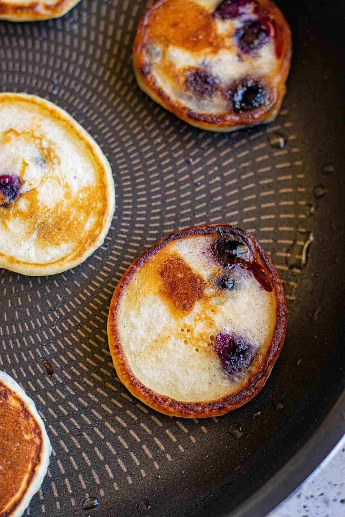Panqueques mini perfectamente cocidos en una sartén.