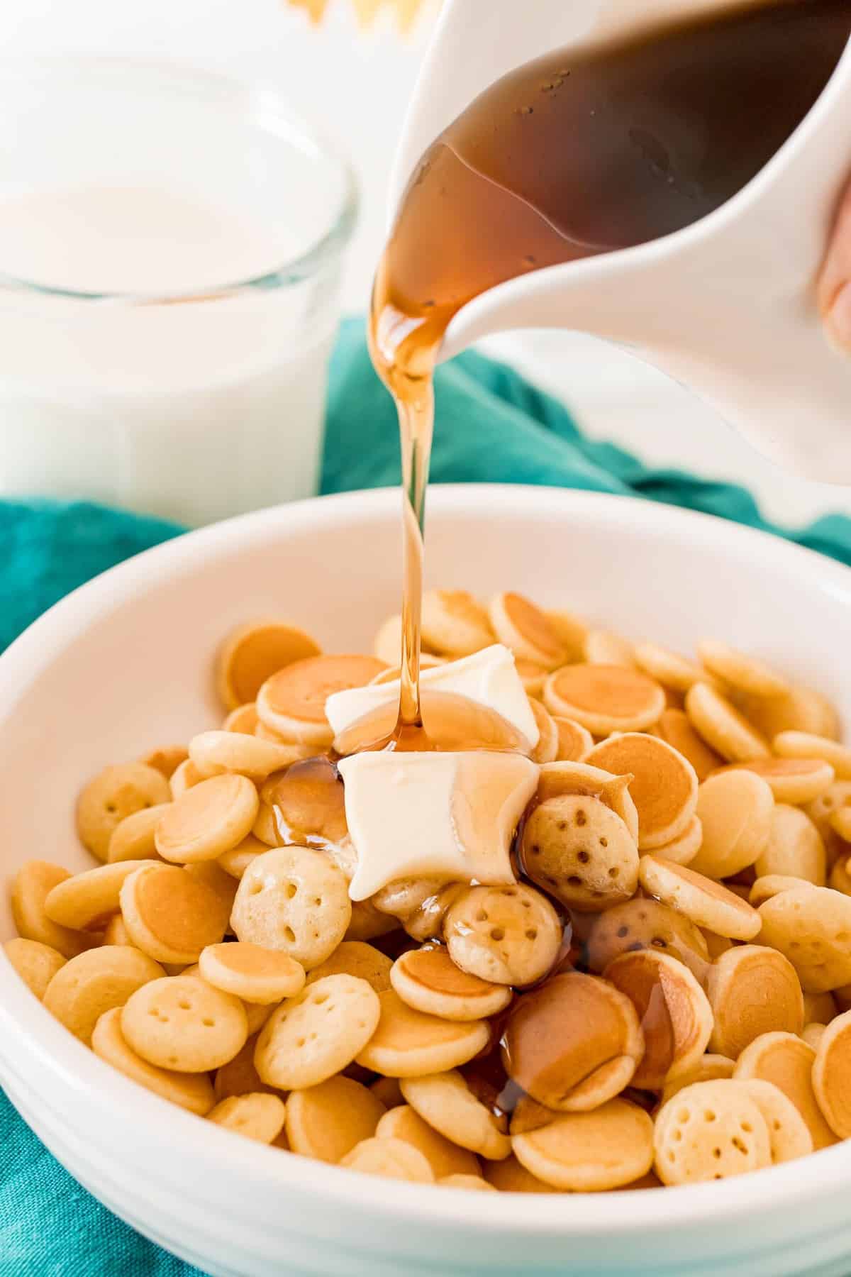 Sirope siendo vertido sobre un tazón de cereal de panqueques.