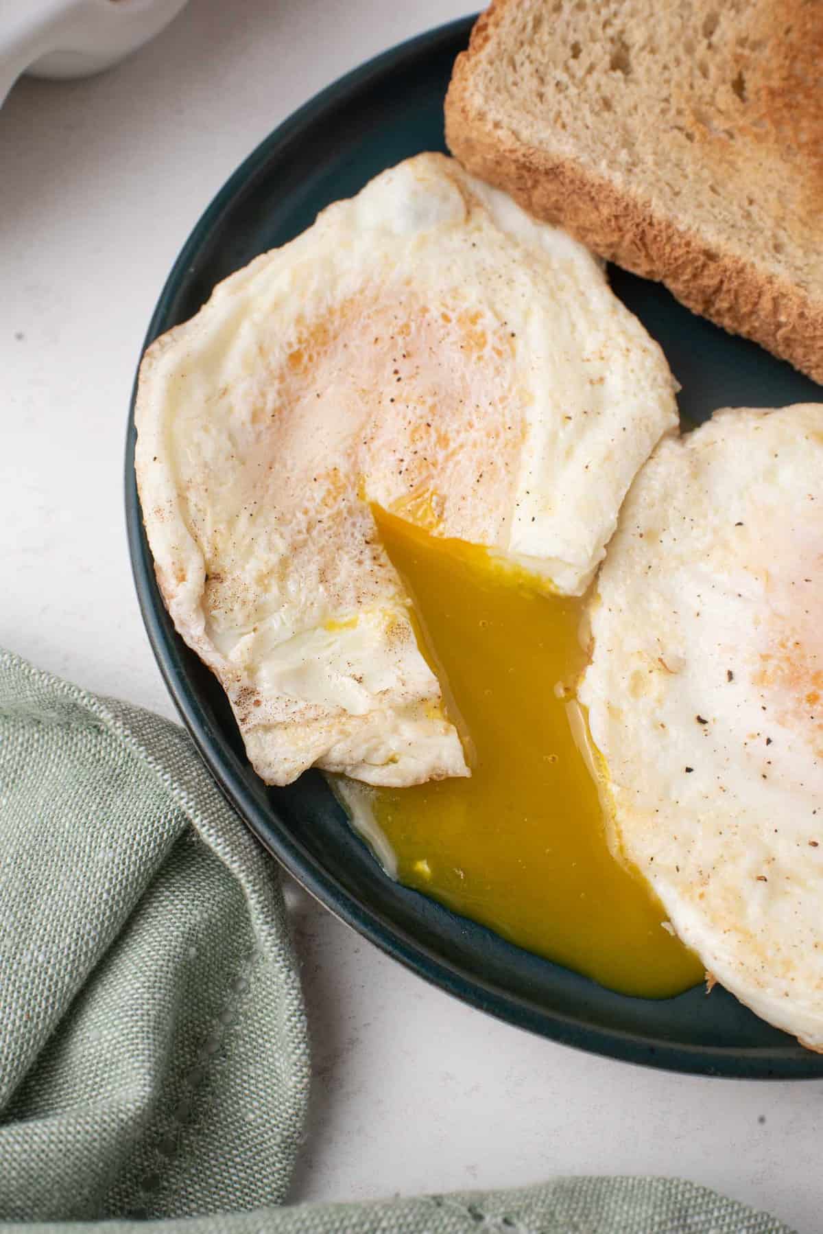Dos huevos cocidos rotos, con la yema de uno fluyendo en el plato.